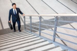 Businessman with briefcase about to climb a stairway at first day of new life