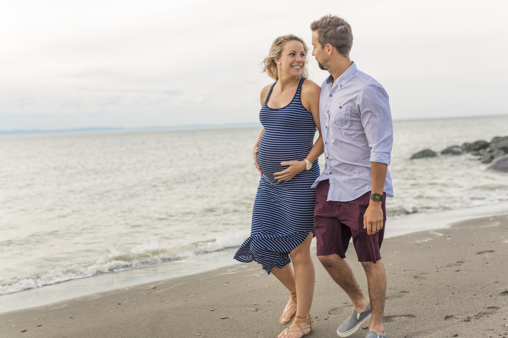 Happy parents-to-be walking on the beach.