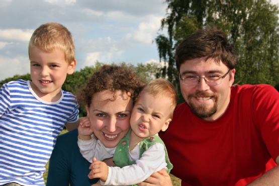 family with two children closeup on meadow and trees