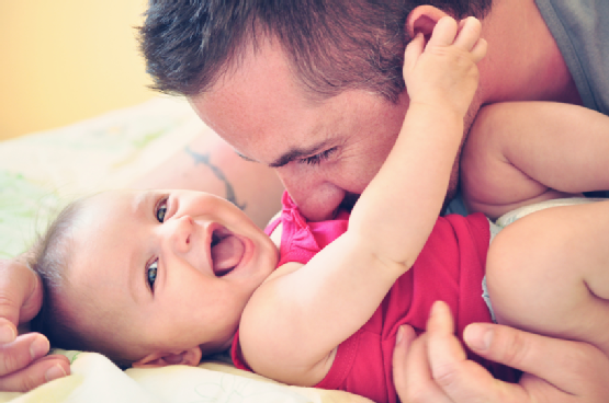 Father playing with his happy and smiling baby daughter